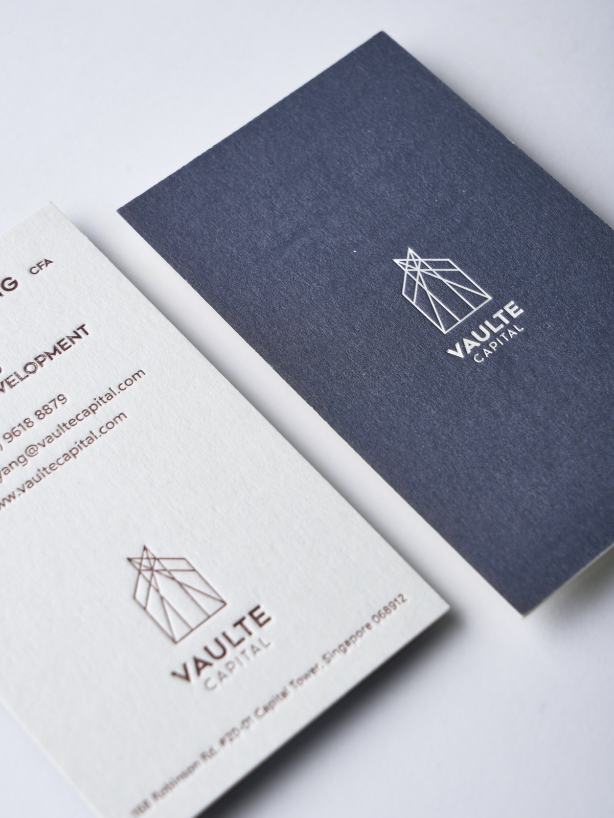 A navy and white business-card pair with a fine outlined emblem.