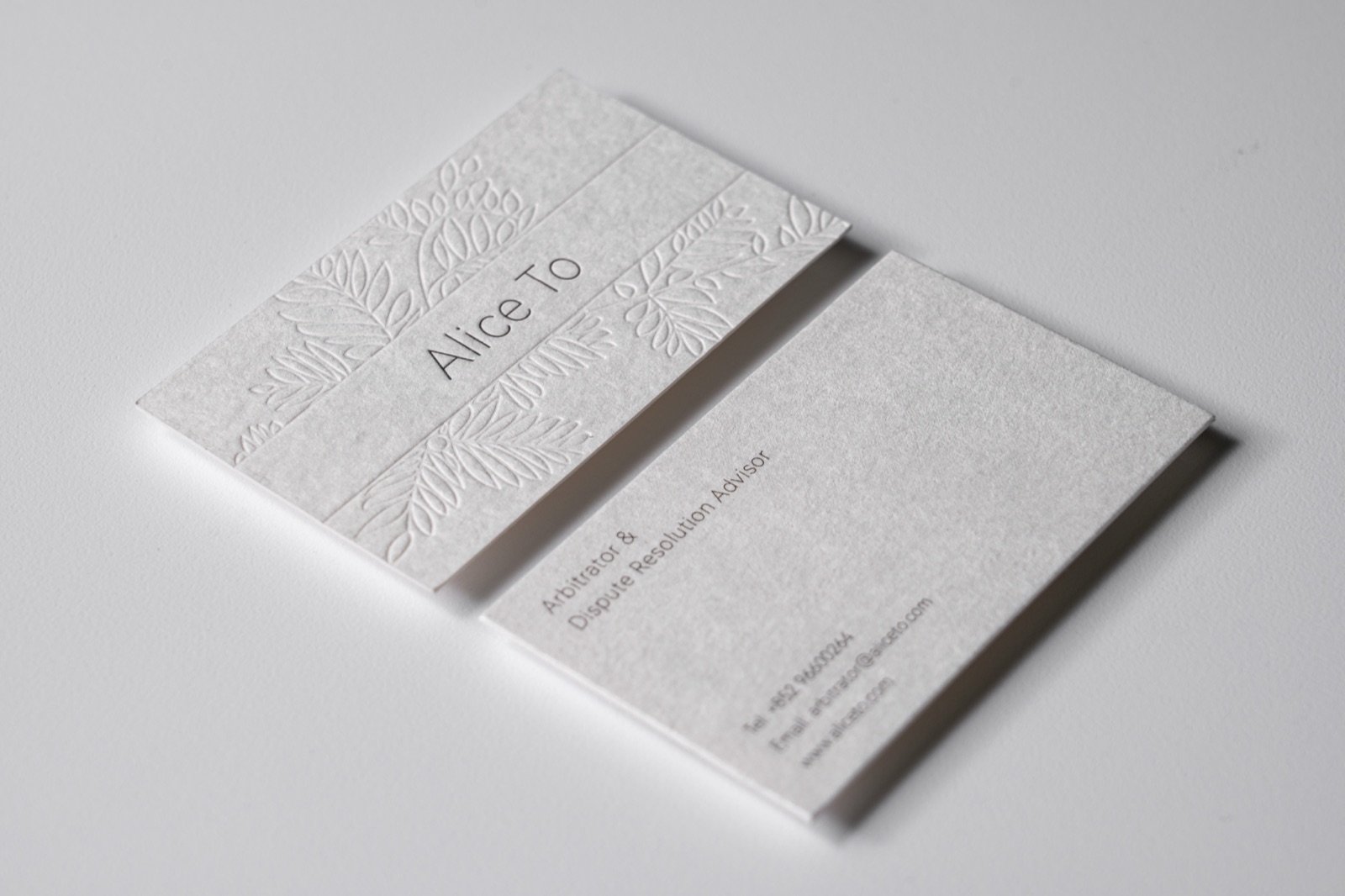 A white card pair with a large tone-on-tone botanical relief across the front.