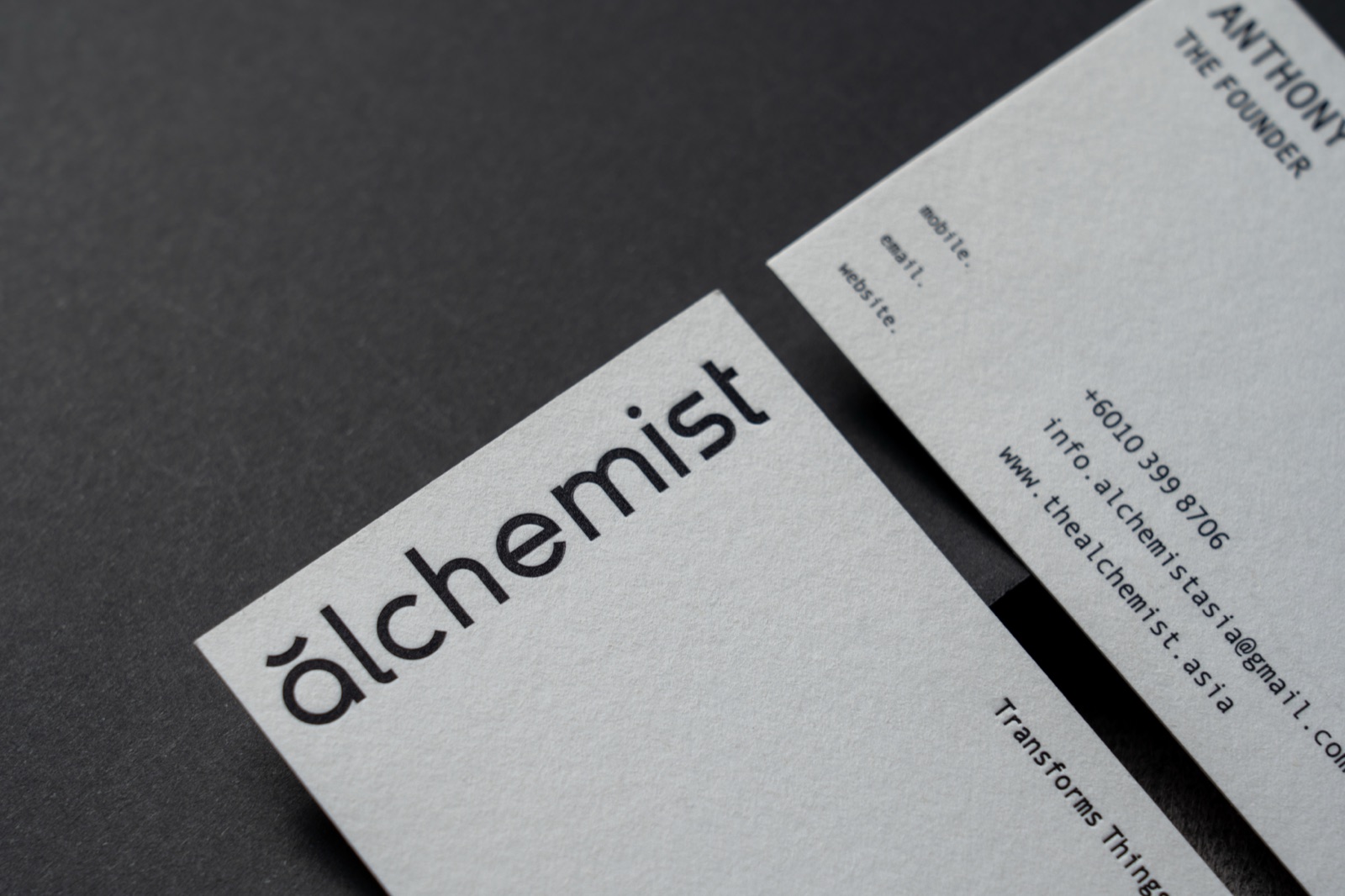 White business cards with large black editorial typography and fine contact text.