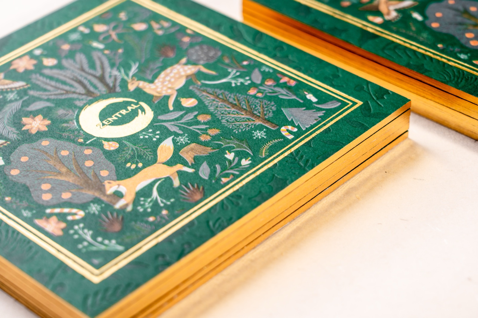 Illustrated forest-green cards with reflective gold frames and gold-coloured edges.