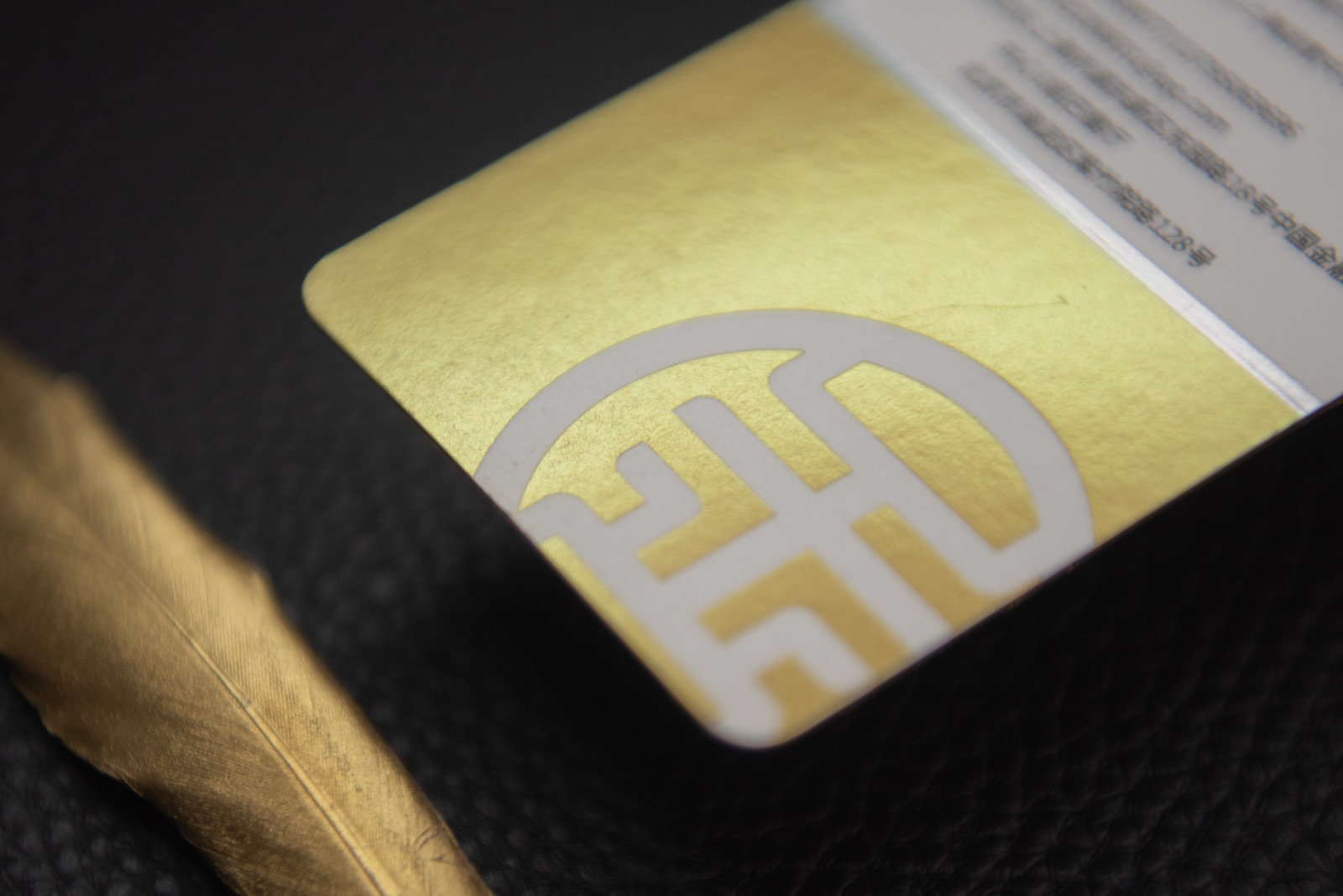 A close view of a white card with a broad metallic gold area and a large reverse-out mark.