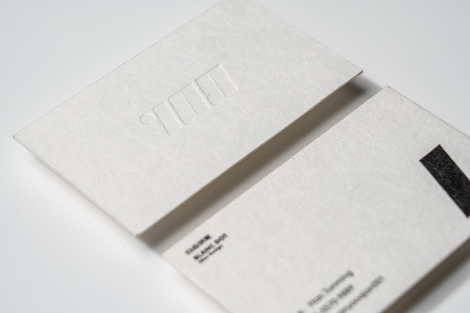 A close view of pale cards with a recessed letterform and a softly textured surface.