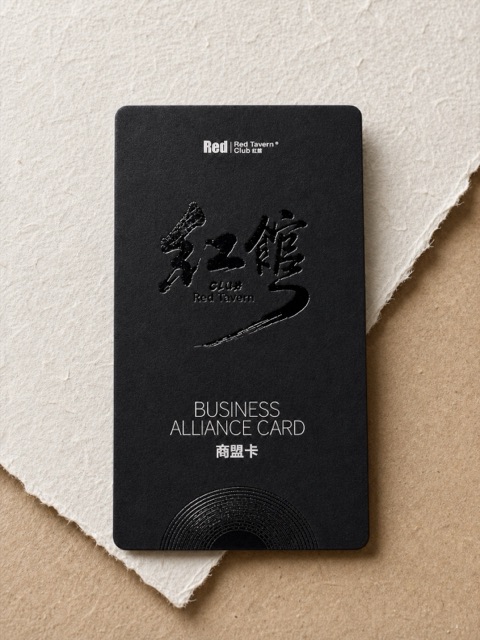 A vertical black card with dark calligraphic marks and small pale lettering.