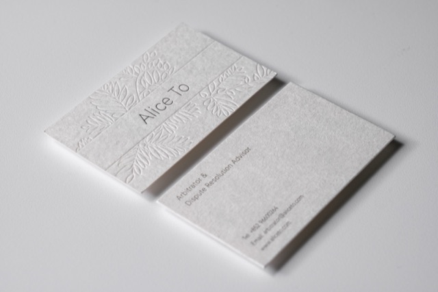 A white card pair with a large tone-on-tone botanical relief across the front.