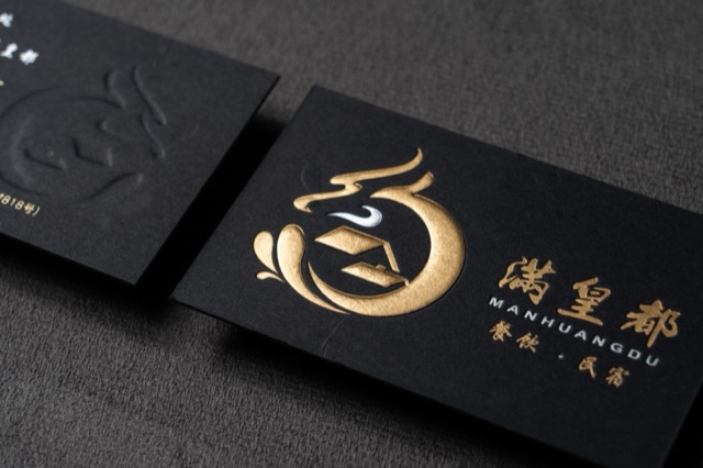 A black card with a sculptural-looking gold symbol beside a dark tone-on-tone version.