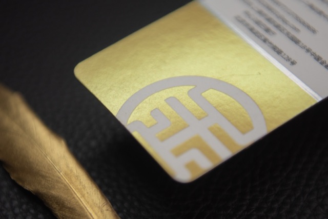 A close view of a white card with a broad metallic gold area and a large reverse-out mark.