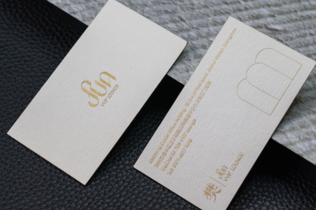 A white card pair carrying a gold-coloured symbol and fine outline graphics.