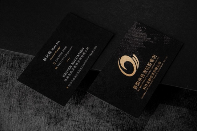 A black card pair with a large reflective gold spiral-like emblem.