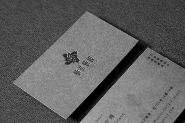 Grey textured cards with a dark floral mark and indented-looking fine text.