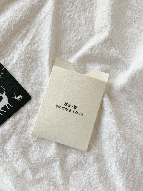 An ivory stationery sleeve with a small dark mark, photographed on white fabric.
