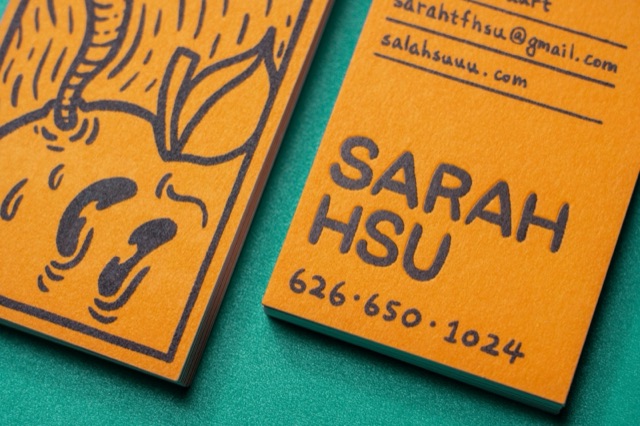 A close view of orange cards with bold black illustration and display lettering.