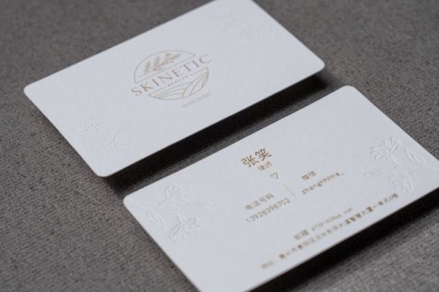 White cards with rounded corners, a fine circular emblem and pale gold-coloured text.