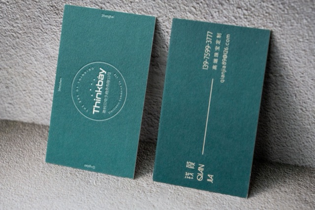 A teal card pair combining a small outlined round mark with gold-coloured contact text.