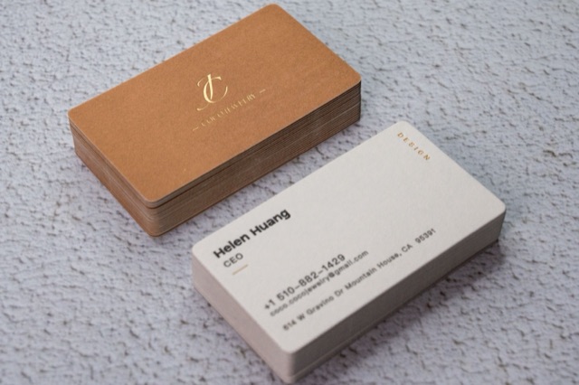 A warm metallic-looking card stack beside pale rounded cards on a light textured surface.